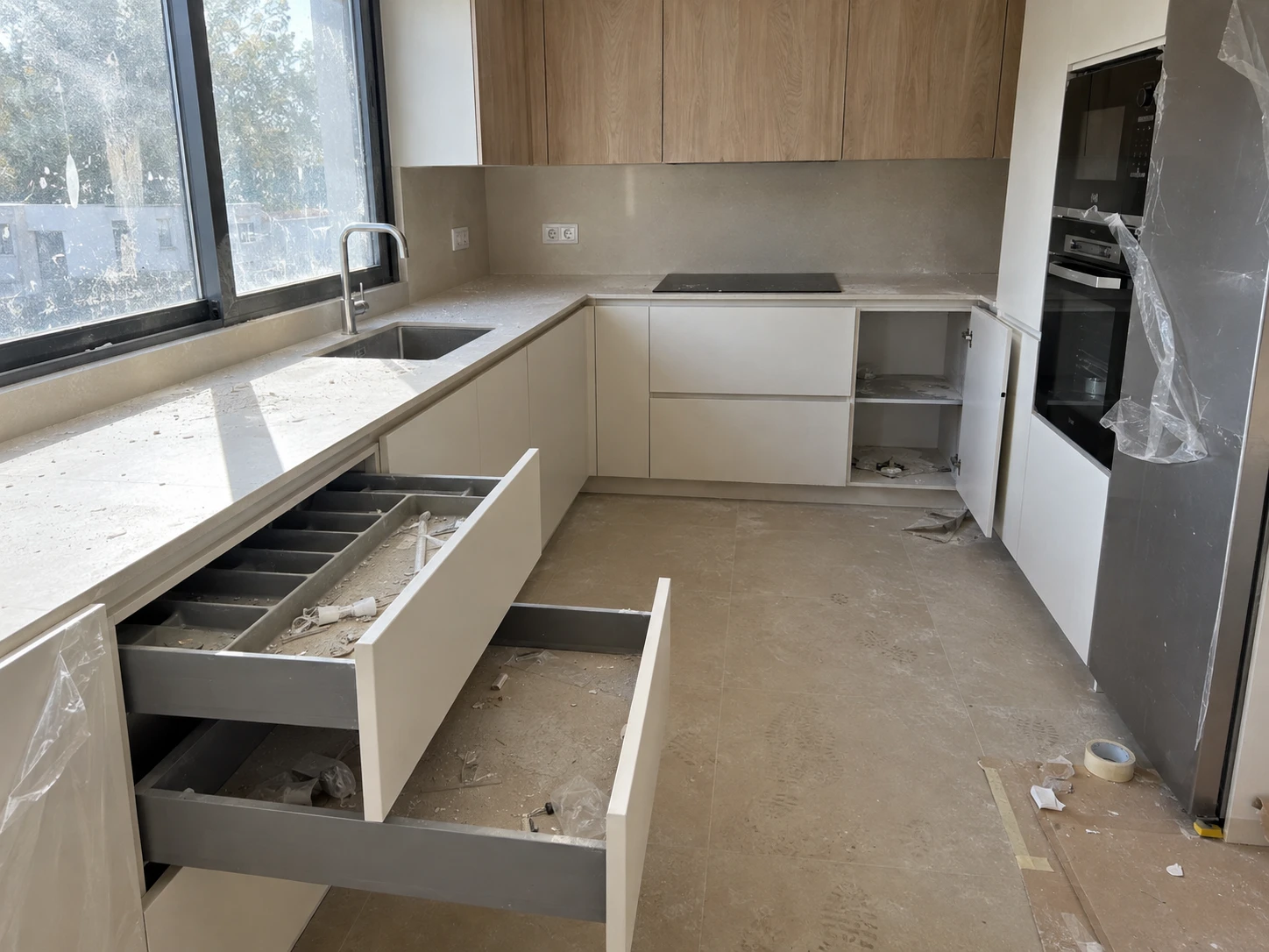 Cocina nueva con los electrodomésticos aún envueltos en plástico de protección, antes y después de la limpieza fina de obra — sin tratar