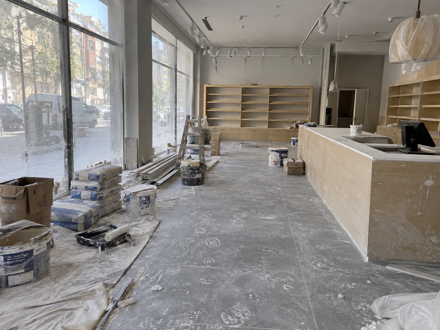 Local comercial con estanterías y mostrador de madera, antes y después de la limpieza final de obra — sin tratar