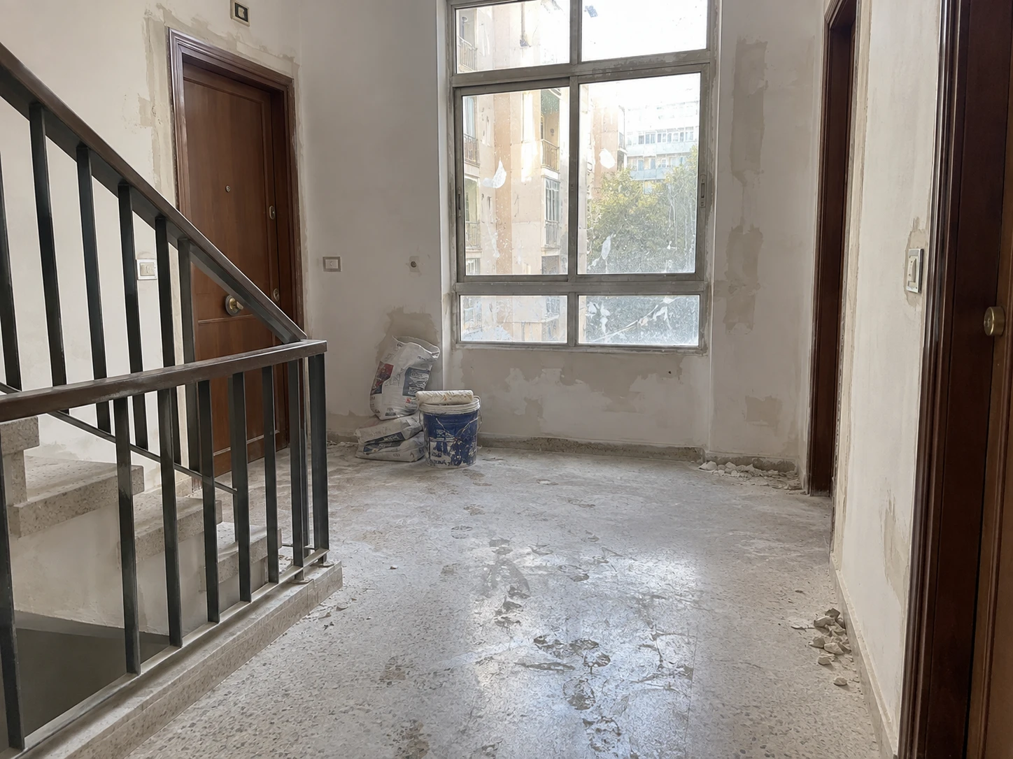 Rellano de una escalera de vecinos, antes y después de la limpieza de obra — sin tratar